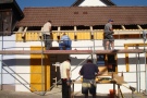 Fünf Männer arbeiten an der Dacheindeckung eines Gebäudes.