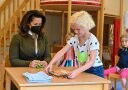 Ein Kind zeigt Ministerin Kaniber, wie es ein T-Shirt faltet