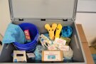 Verleihkiste mit Kuscheltieren, Lebensmittelattrappen, blauen Putzeimern, blauen Lappen