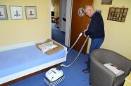 Ein Senior staubsaugt ein Zimmer