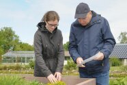 Junge Frau und älterer Herr stehen an einem Hochbeet