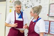 Zwei Personen in Küchenkleidung besprechen einen Plan