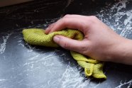 Eine Hand wischt eine Fläche mit einem Spüllappen ab