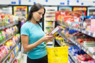Frau liest im Supermarkt Verpackung durch