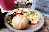 Brötchen, Eier mit Kresse, Radieschen, Obst und Gemüse auf einem Teller angerichtet