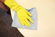 Eine behandschuhte Hand wischt einen Tisch