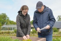 Junge Frau und älterer Herr stehen an einem Hochbeet
