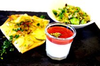 Auf einer Platte finden sich ein Joghurt mit pürierten Früchten, Flammkuchen und Salat