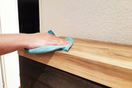 Eine Person wischt einen Schrank mit einem Lappen ab