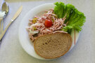 Teller mit Wurstsalat und Brotscheibe