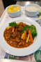 Teller mit Gulasch und Beilagen auf Tablett