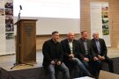 Vier Männer sitzen am Rande der Bühne