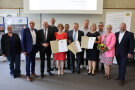 Eine Gruppe von Menschen, drei halten eine Urkunde