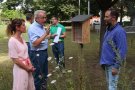 Personen von links: Cornelia Schiller-Thelen Sachgebietsleiterin Landespflege ALE Oberfranken, Lothar Winkler Amtsleiter ALE Oberfranken, Mario Remmele MR Bamberg, stehen um eine Nisthilfe aus Holz.