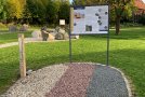 Verschiedene Gesteine in einem Park mit Infotafel.