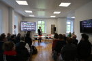 Ein Saal voller Menschen vor denen Daniel Weißerth spricht. 