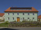 Ein grünes Haus mit grünem Vorgarten