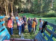 Eine Gruppe Menschen steht auf einer Wiese mit Bäumen im Hintergrund 