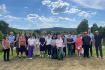 Viele Personen stehen nebeneinander, dahinter der blaue Himmel