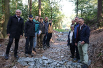 Vertreterinnen und Vertreter des ALE, der Gemeinde, des Planungsbüros und der Baufirma stehen im Wald am Ort der Maßnahme.