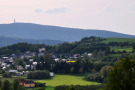 Ein Dorf, das an einem Hang liegt, im Hintergrund ein Höhenzug des Fichtelgebirges.