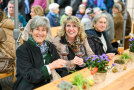 Drei Frauen am Biertisch genießen die Köstlichkeiten des Käsegenussmaktes.
