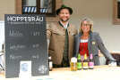 Eine Frau und ein Mann neben einer Schiefertafel. Sie verkaufen Bier von Hoperbräu.